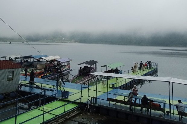 Wisata perahu di Telaga Menjer Wonosobo dengan latar dermaga dan perbukitan yang asri.